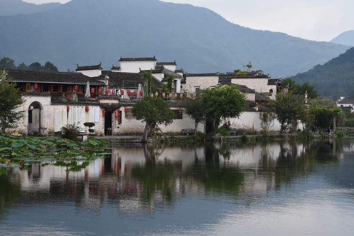 Traditional Chinese architecture by a lake with mountains