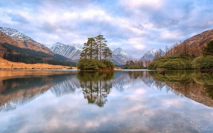 Island with trees in a lake with mountains