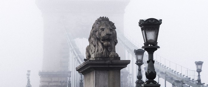 Stone lion statue on a bridge in the mist