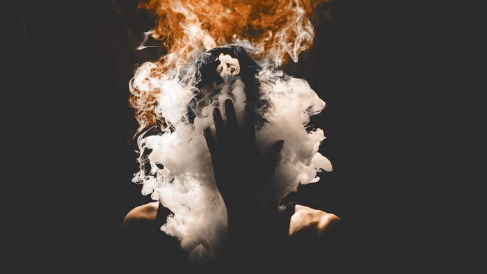 Person covered in smoke with fire above