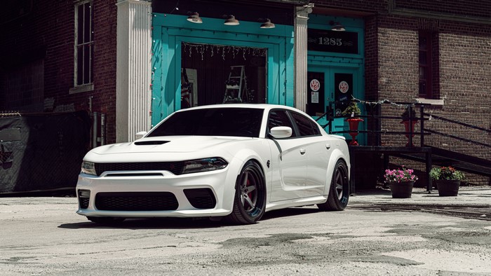 White Dodge Hellcat car parked in front of a brick building