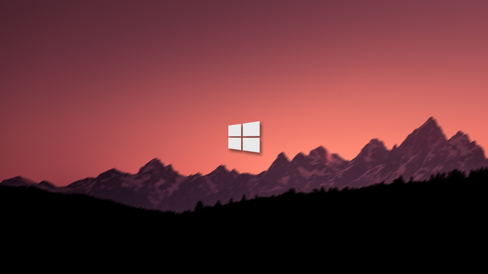 Microsoft Windows logo over blurred mountains at sunset