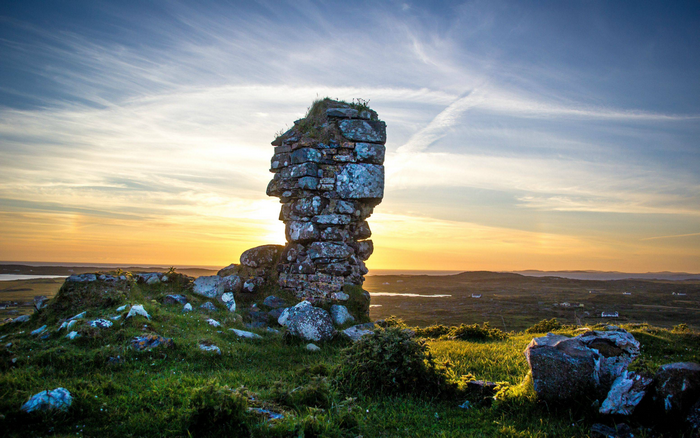 Stone ruins on a grassy hill at sunset in Ireland