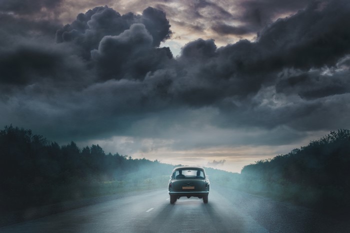 Car driving on a road under stormy clouds