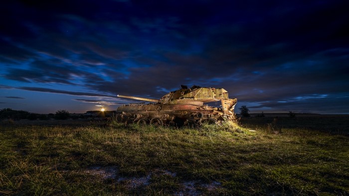 Abandoned tank in a field at night