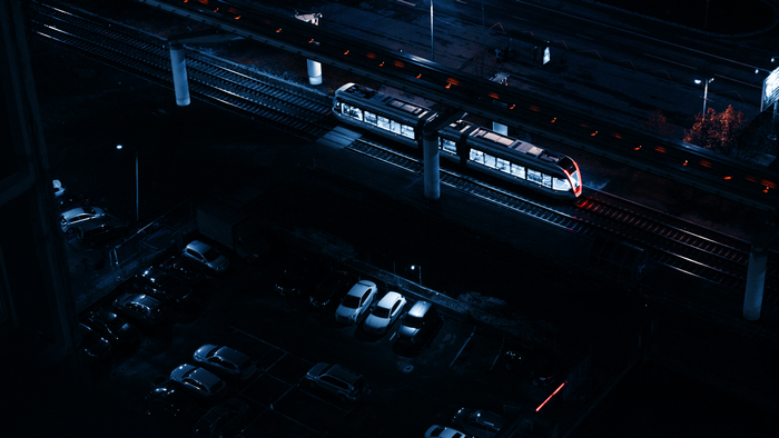 Train on railroad tracks at night with parking lot