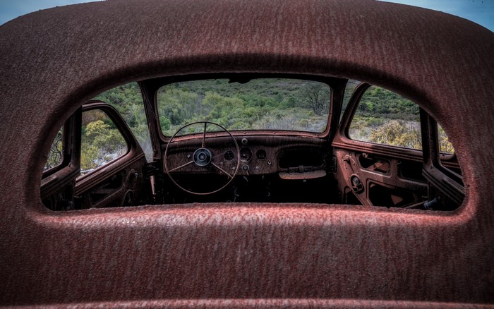 Interior of a rusty, abandoned car overlooking a landscape