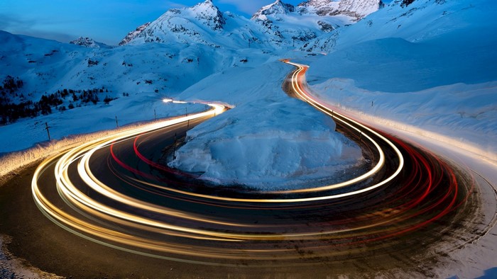 Light trails on a snowy mountain road at dusk