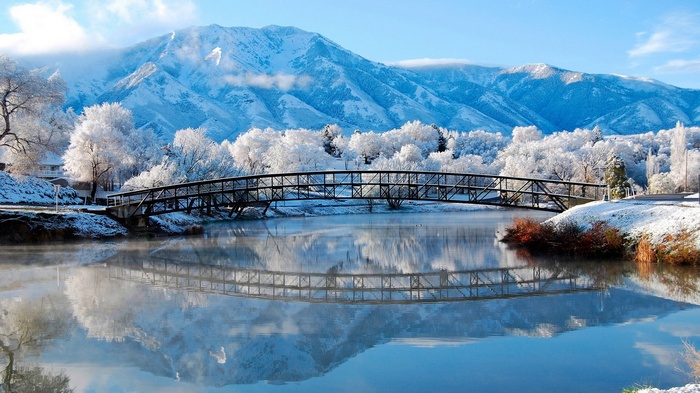 Snowy bridge over a river with mountains in the background
