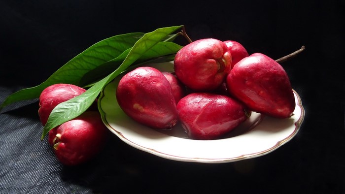 Red rose apples with leaves on a plate
