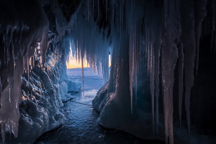 Ice cave with icicles and sunset view in Russia