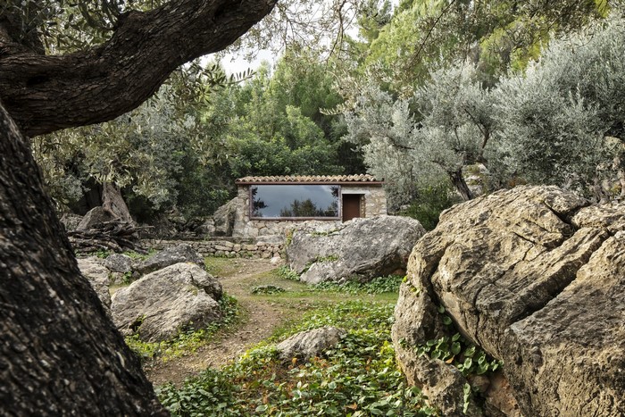 Stone cottage with large window in a forest