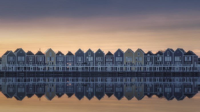Row of colorful houses reflected in water at sunset