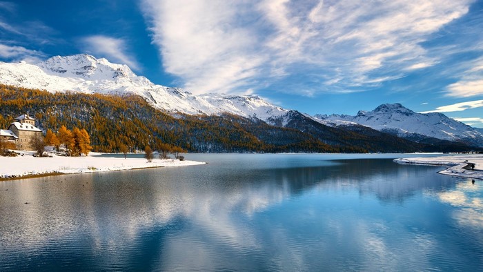 Snowy mountains and lake in Switzerland with a house