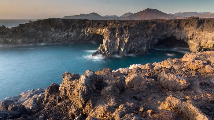 Volcanic coast with sea arch and mountains, Lanzarote