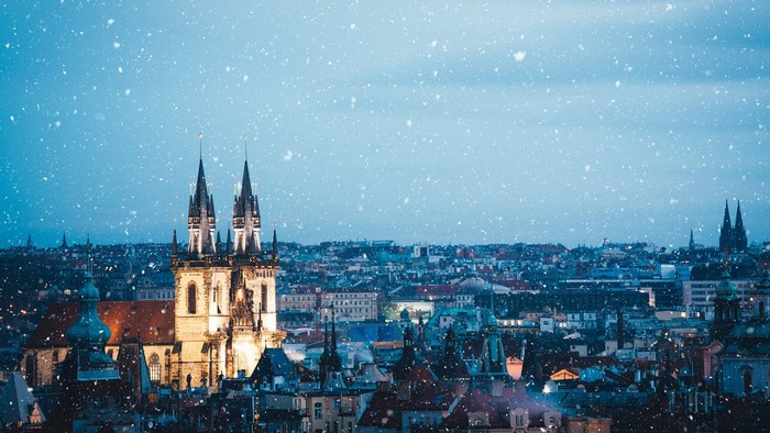 Prague cityscape with snow falling at dusk