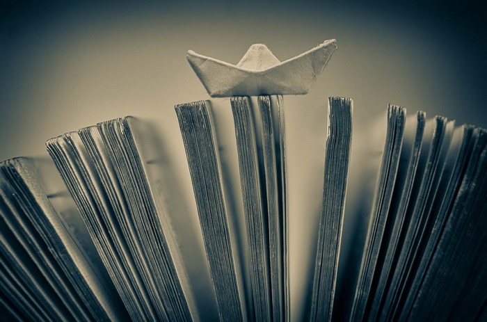Origami paper boat on open books