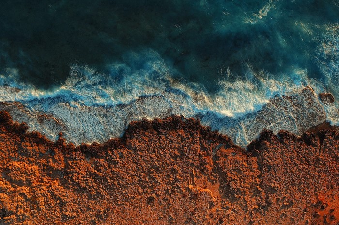 Aerial view of ocean waves crashing on a rocky coast