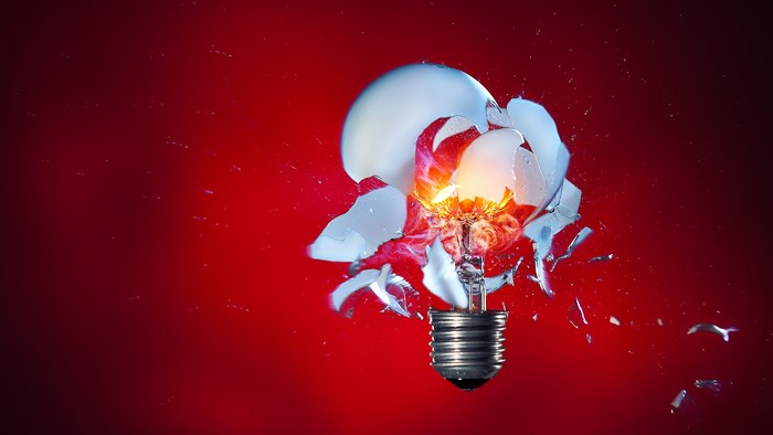 Exploding light bulb with red background