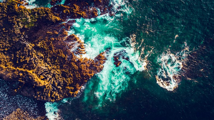 Aerial drone photo of waves crashing on rocky coast