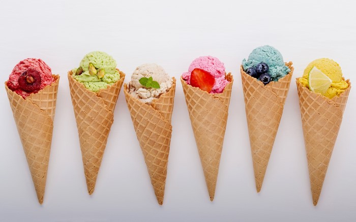 Six ice cream cones with various toppings on a white background