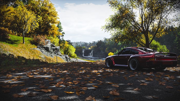 Red Porsche 959 on a road with autumn leaves
