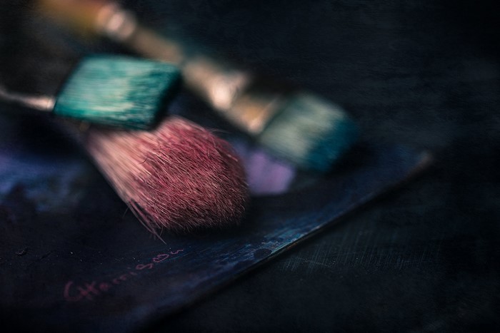 Paint brushes on a dark surface with signature