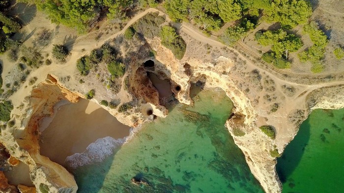 Aerial view of a rocky coastline with caves and clear water