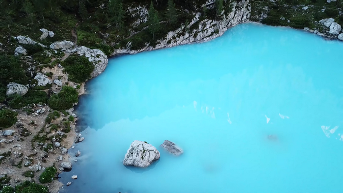 Bright blue lake surrounded by rocky shore and trees