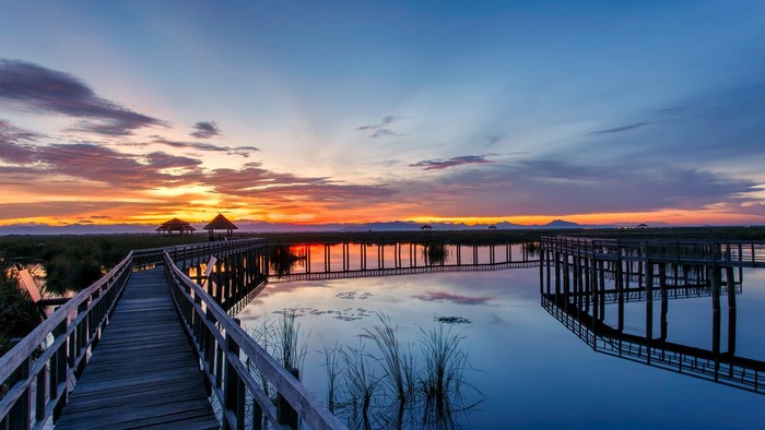 Wooden walkway over water at sunrise in Thailand