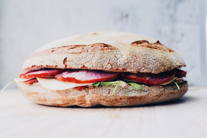 Sandwich with meat, cheese, and greens on bread