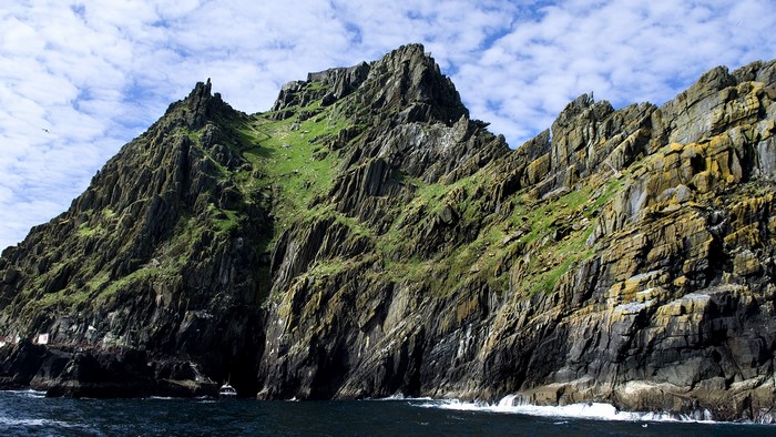 Jagged rocky island with green grass and blue sky