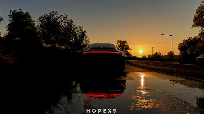 Dark car on wet road at sunset