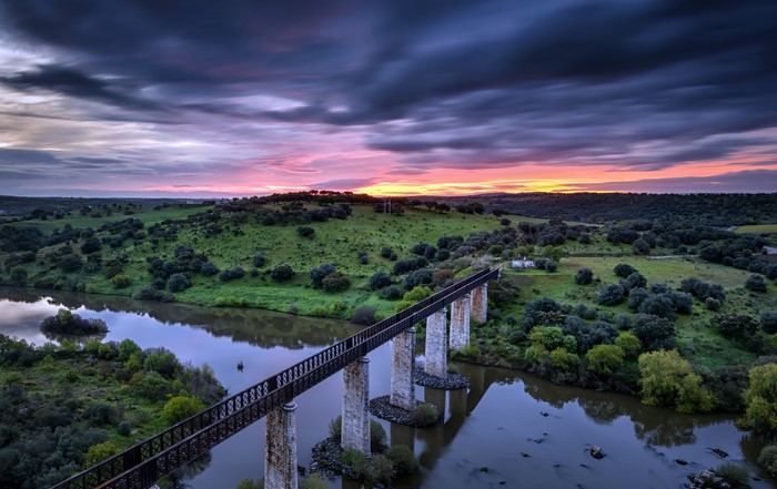 Bridge over river at sunset with dramatic sky