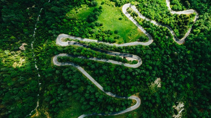 Aerial view of a winding road through a green forest