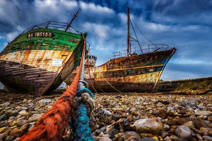 Two abandoned fishing boats on a rocky shore
