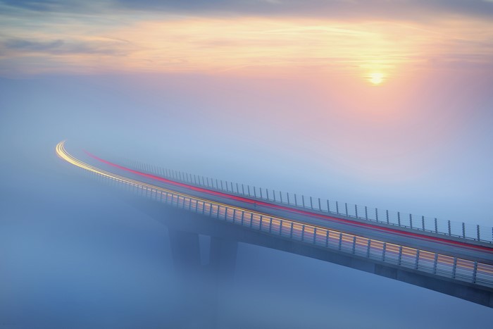 Bridge in mist with light trails at sunrise