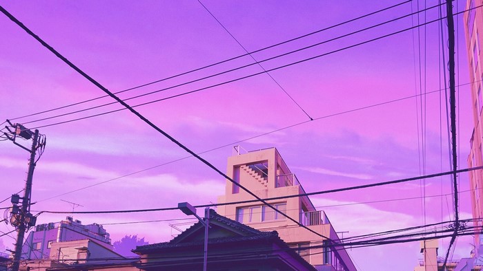 City buildings and power lines under a purple sky