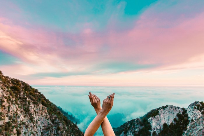 Hands crossed over clouds and mountains