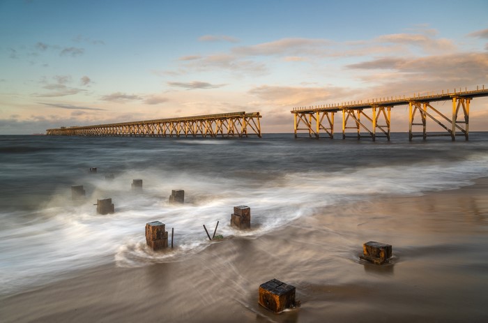 Broken wooden pier on the coast of England at sunset