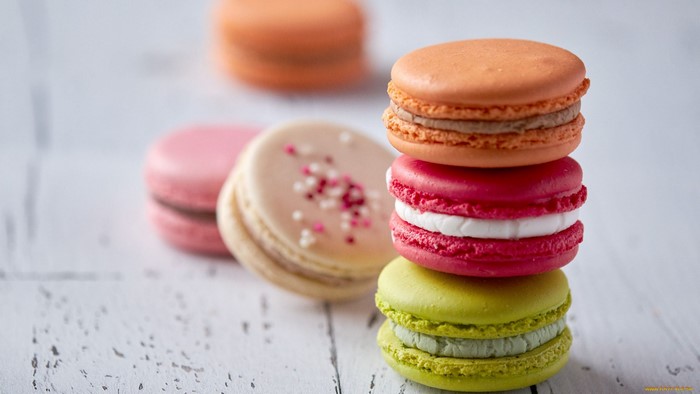 Stack of colorful macarons on a white wooden surface