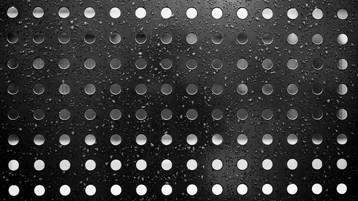 Black perforated surface with water drops