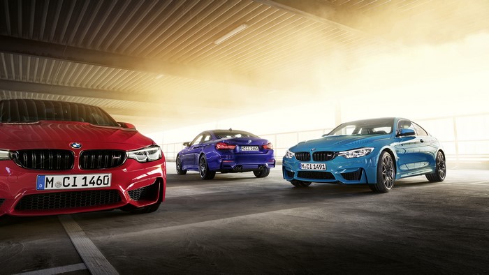 Three BMW M4 cars in a parking garage