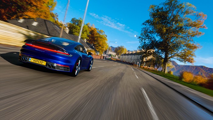 Blue Porsche 911 Carrera 4S driving on a road in autumn