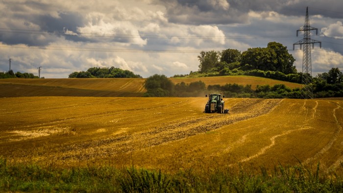 Tractor plowing a golden field under a cloudy sky