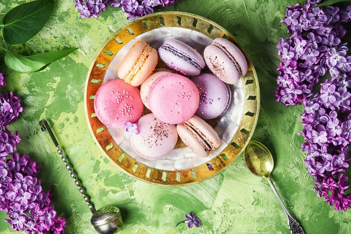 Colorful macarons on a decorative plate with lilacs