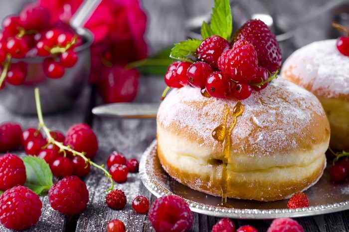Donut with berries and honey on a wooden table