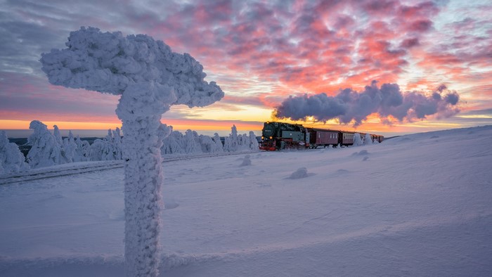 Steam train in a snowy landscape at sunset