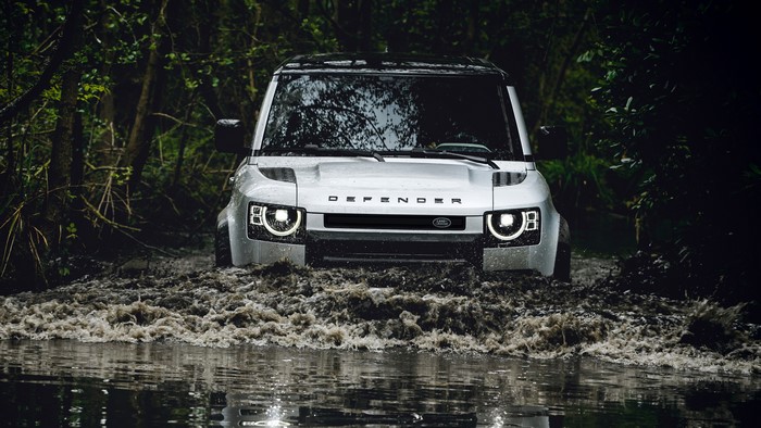 4K Land Rover Defender driving through a forest river