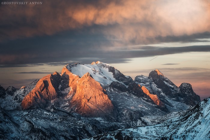 Mountain range with snow and clouds at sunset